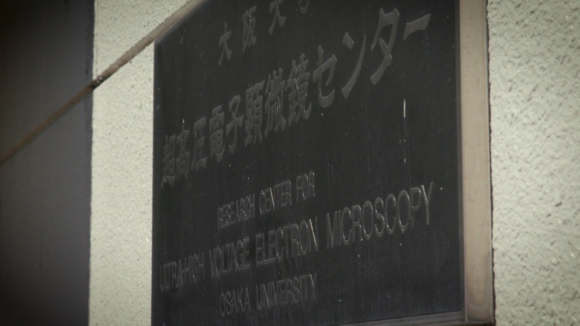 画像: 大阪大学の「超高圧電子顕微鏡センター」の看板が写っている画像です。この施設は科学研究や高精度な分析に使用されます。関連キーワード: 大阪大学、電子