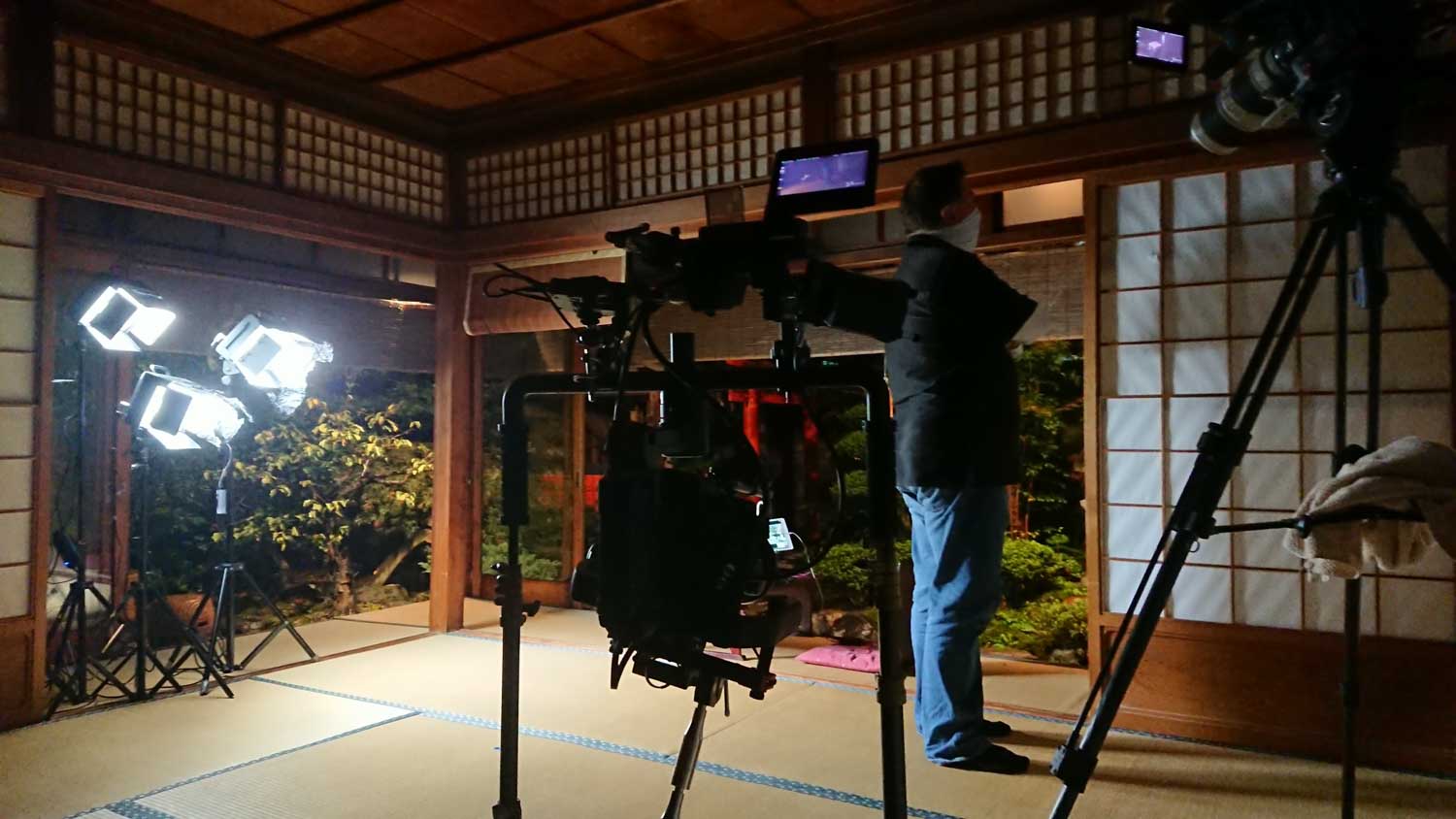 画像: 和風の部屋で映画撮影が行われています。畳の上にカメラと照明機材がセットされ、撮影スタッフが準備中です。背景には和紙の障子と日本庭
