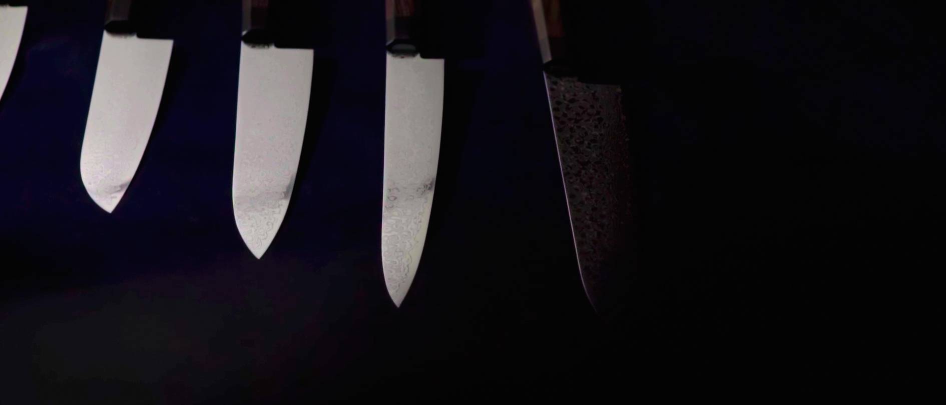 画像: 黒い背景に配置された4本の日本包丁の刃が、鋭く光を反射しています。包丁、キッチンツール、鋭い刃、料理器具、日本の伝統がキ